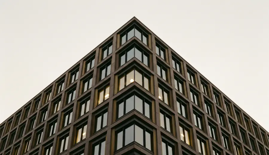 The upper corner of a stone and glass office building at dusk